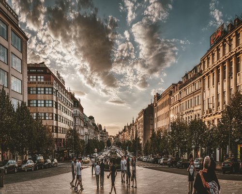 A group of people walking and active outdoors in a historic city square under warm sunshine
